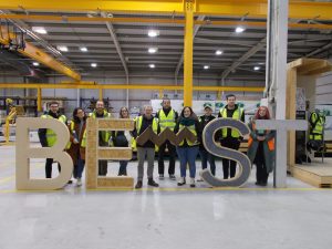 Robin Mackenzie Team behind the timber made BE-ST logo at Built Environment – Smarter Transformation in Hamilton.